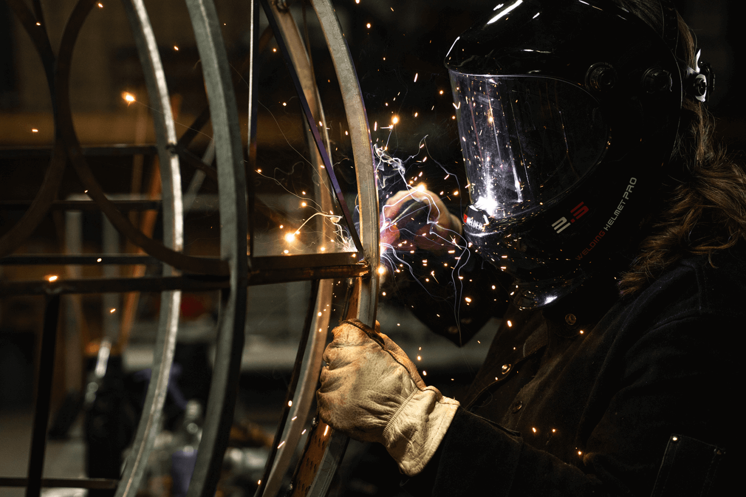 Female artist welding in her sculpture studio